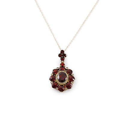 Exquisite silver gilt pendant on a silver chain, set with thirteen deep red old cut garnets and a larger oval garnet surrounded by marcasites in the centre.