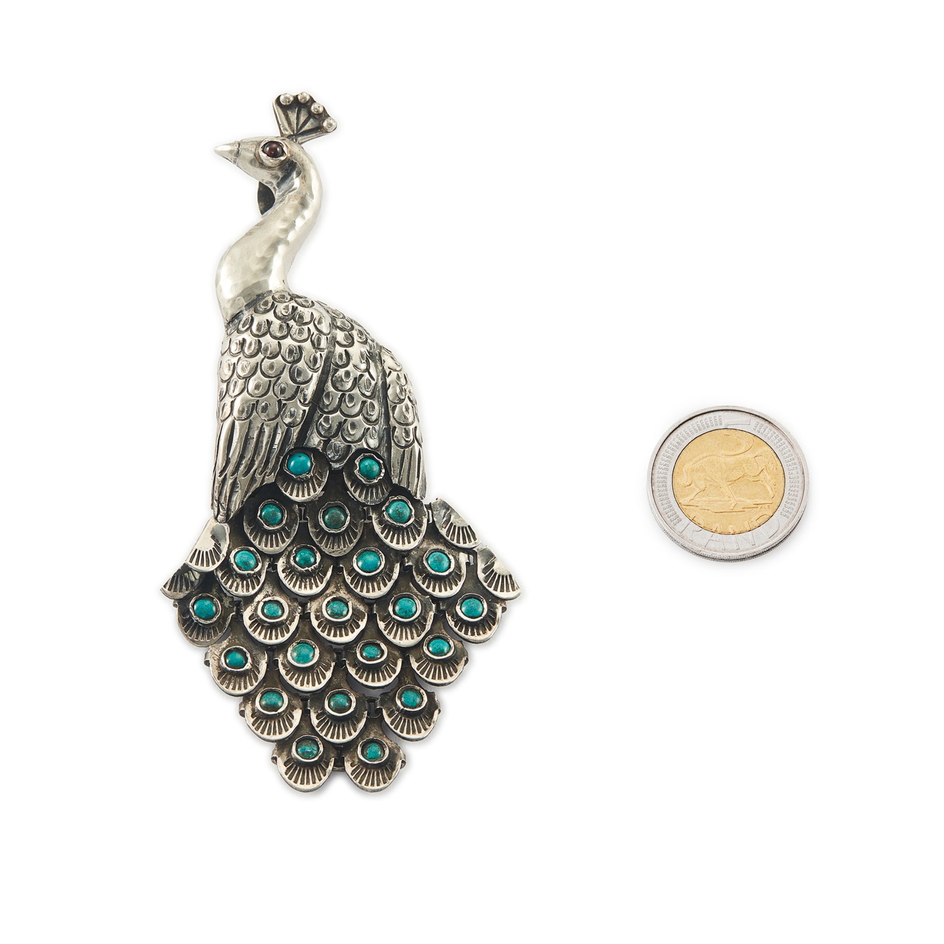 Magnificent Mexican oxidised high grade silver peacock pendant/brooch with twenty-three cabochon turquoise stones set in its articulated tail feathers, with a garnet eye. 