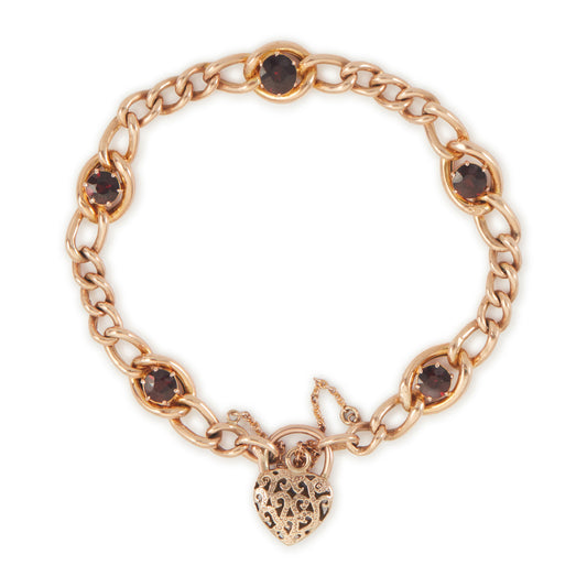 Classic Victorian 9ct rose gold curb link bracelet set with five deep red garnets, finished with an ornate heart padlock. Safety chain attached.