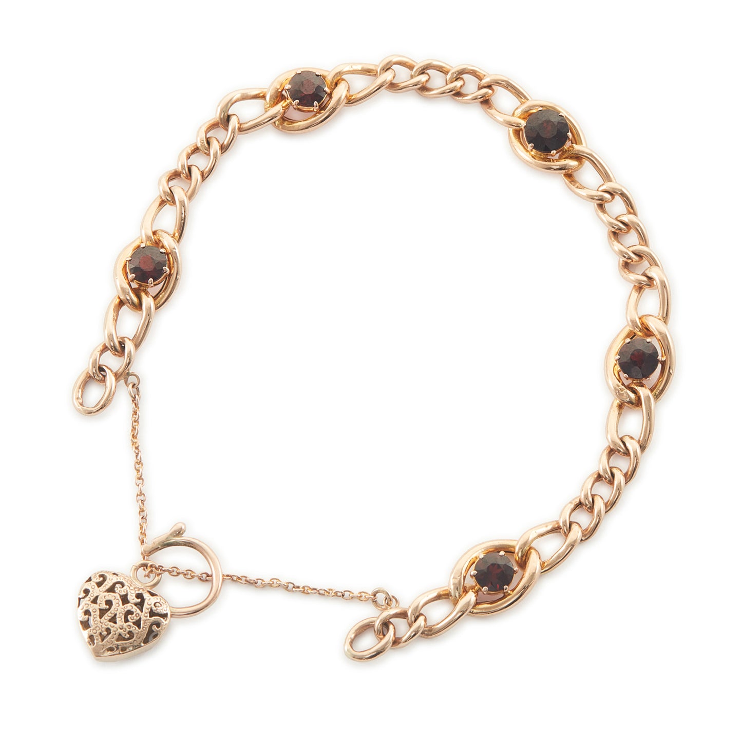 Classic Victorian 9ct rose gold curb link bracelet set with five deep red garnets, finished with an ornate heart padlock. Safety chain attached.