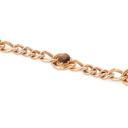 Classic Victorian 9ct rose gold curb link bracelet set with five deep red garnets, finished with an ornate heart padlock. Safety chain attached.