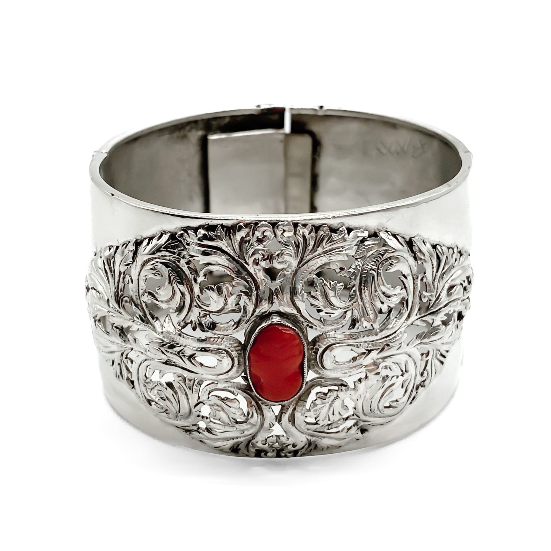 Gorgeous Victorian silver bangle set with a natural Mediterranean coral cameo and two coral stones on the clasp. The bangle has intricate detail.