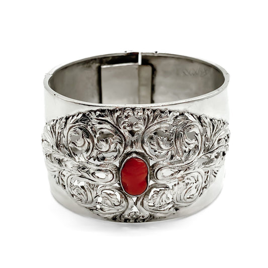 Gorgeous Victorian silver bangle set with a natural Mediterranean coral cameo and two coral stones on the clasp. The bangle has intricate detail.