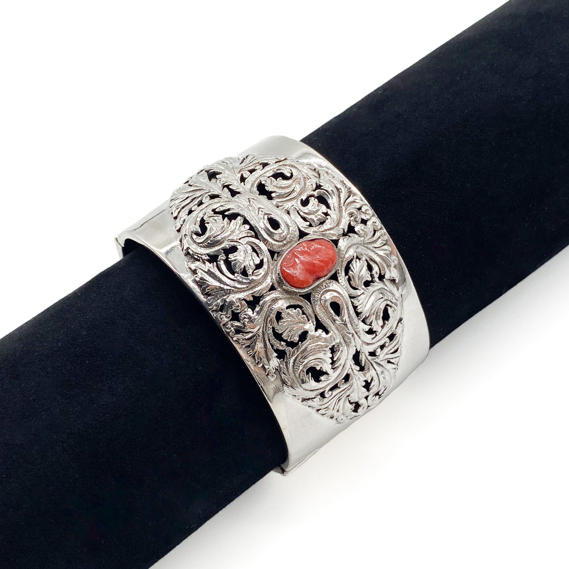 Gorgeous Victorian silver bangle set with a natural Mediterranean coral cameo and two coral stones on the clasp. The bangle has intricate detail.