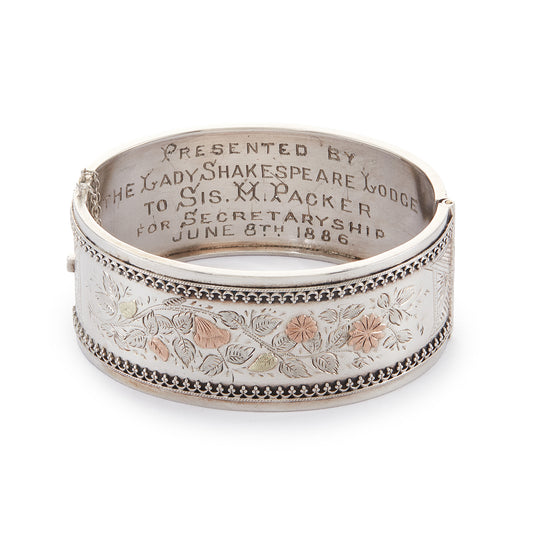 Beautiful Victorian silver and gold bangle embossed with a floral design and Etruscan detail around the rim. Safety chain attached.