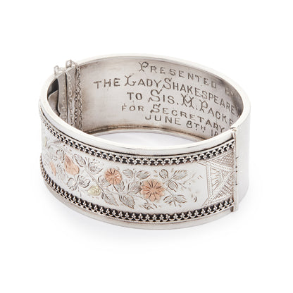 Beautiful Victorian silver and gold bangle embossed with a floral design and Etruscan detail around the rim. Safety chain attached.