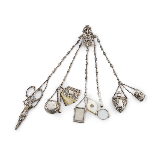 Magnificent Victorian sterling silver chatelaine with household tools dangling from chains with dog clips. The decorative belt hook holds a of a pair of scissors, a pencil, a pill box, a miniature note pad, a lorgnette with mother of pearl casing, a beautiful vinaigrette with silver-gilt inside, a shoe hook, a perfume bottle and a thimble holder with a thimble inside.