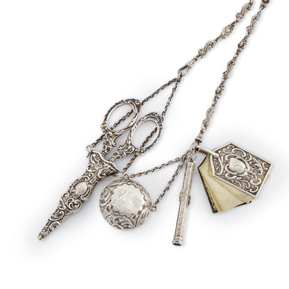 Magnificent Victorian sterling silver chatelaine with household tools dangling from chains with dog clips. The decorative belt hook holds a of a pair of scissors, a pencil, a pill box, a miniature note pad, a lorgnette with mother of pearl casing, a beautiful vinaigrette with silver-gilt inside, a shoe hook, a perfume bottle and a thimble holder with a thimble inside.