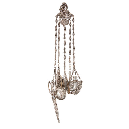 Magnificent Victorian sterling silver chatelaine with household tools dangling from chains with dog clips. The decorative belt hook holds a of a pair of scissors, a pencil, a pill box, a miniature note pad, a lorgnette with mother of pearl casing, a beautiful vinaigrette with silver-gilt inside, a shoe hook, a perfume bottle and a thimble holder with a thimble inside.
