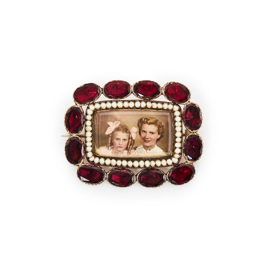 Very unusual Victorian 9ct gold memento mori picture brooch depicting a mother and daughter, surrounded by fine seed pearls and twelve oval shaped deep red old cut garnets.