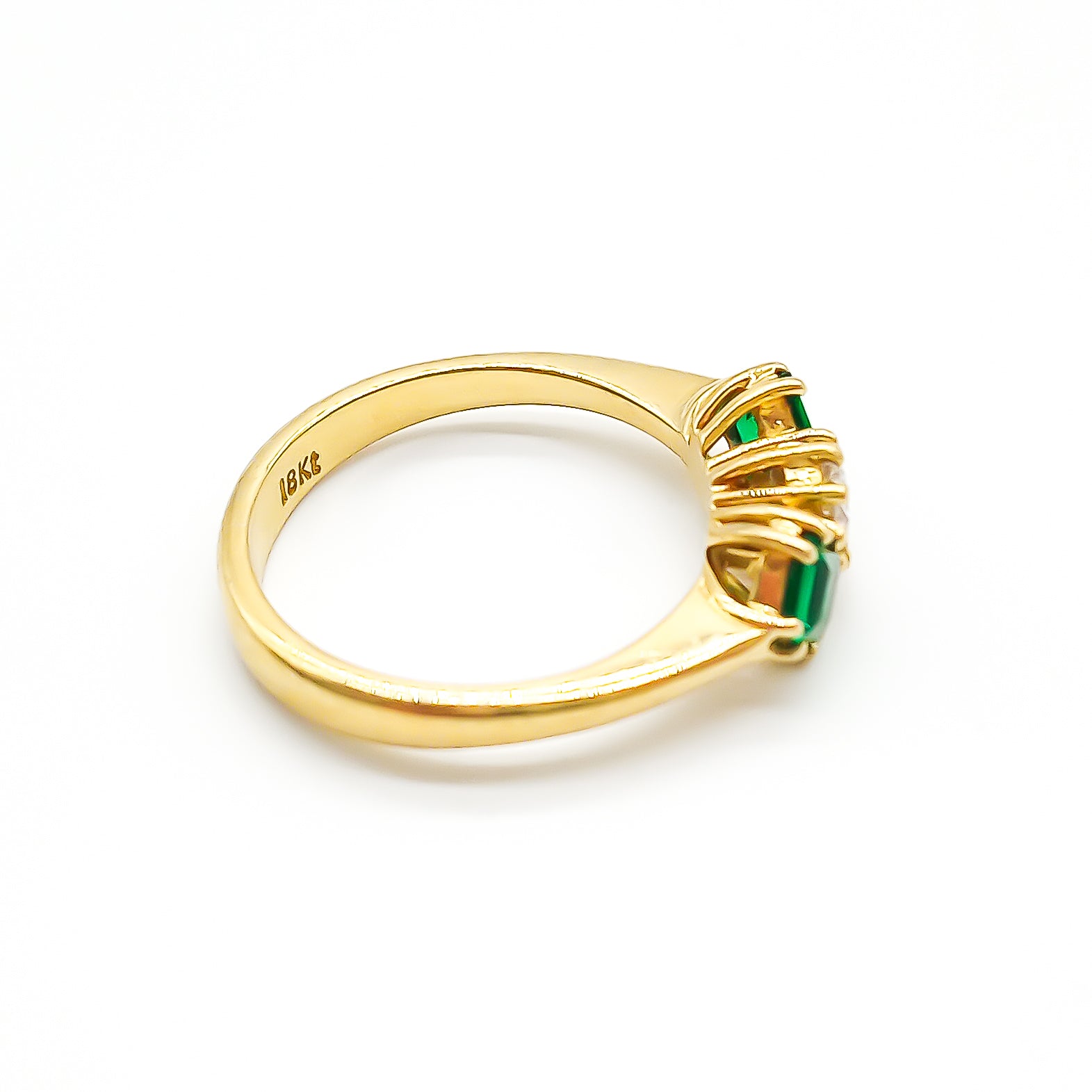 Stunning 18ct yellow gold ring set with a round 0,20ct centre diamond and two bright green princess-cut emeralds.