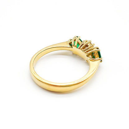 Stunning 18ct yellow gold ring set with a round 0,20ct centre diamond and two bright green princess-cut emeralds.