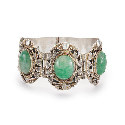 Stunning Chinese silver gilt bracelet set with three oval jade cabochon stones. Two side stones are hand carved with a leaf design. The bracelet is ornately carved with a floral design, also featuring birds and a dragon.