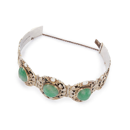 Stunning Chinese silver gilt bracelet set with three oval jade cabochon stones. Two side stones are hand carved with a leaf design. The bracelet is ornately carved with a floral design, also featuring birds and a dragon.